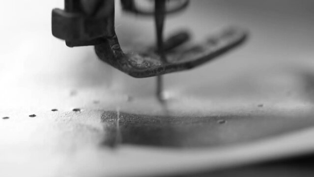 Black and white video where a woman pierces a magazine page with an old fashioned sewing machine. Good footage for video art projects.