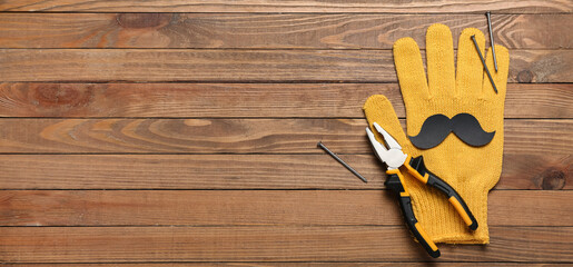 Paper mustache, glove, pliers and nails on wooden background with space for text. Father's Day celebration