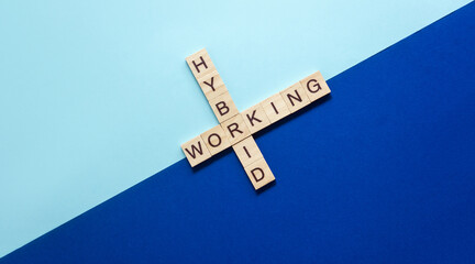 Words Hybrid working from wooden blocks with letters on diagonal dark and light blue background....