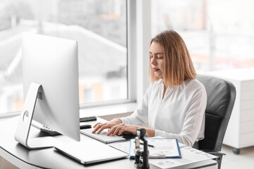 Female accountant working with computer at table in office