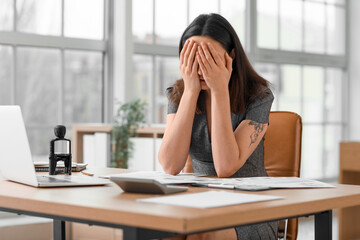 Stressed female accountant working at table in office