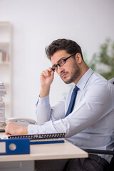 Fototapeta premium Young male employee and too much work in the office