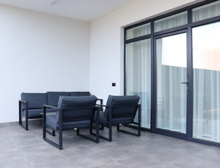 Gray garden furniture on the terrace of a spacious house.