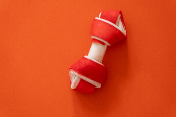 close up of a red Dog bone on orange background. Dog accessories. Minimalistic background.	