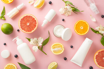 Stylish and juicy summer skincare concept with fruit inspiration. Top view flat lay of mockup cream bottles, jars, serum, pipette with citrus and flower on pastel pink background