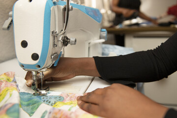 Hands of a dark-haired woman using an industrial sewing machine