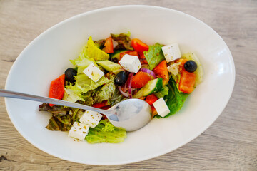 Greek salad in a white plate. dish for the menu of a cafe or restaurant.