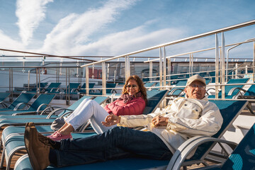 beautiful happy middle aged couple relaxing on deck chairs of a cruise ship