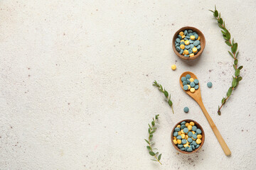 Bowls with pills, spoon and plant branches on white background