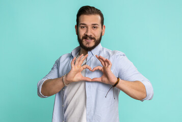 Man in love. Smiling bearded lebanese man 25 years old makes heart gesture demonstrates love sign...