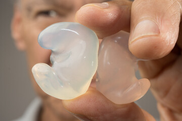 Older Man showing off his custom made silicone earplugs for hearing protection