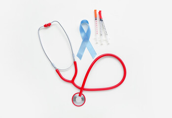 Awareness ribbon with syringes and stethoscope on white background. Diabetes concept