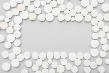 Frame made of white pills on grey background