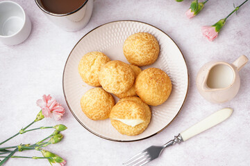 Plate with tasty choux dessert on light background