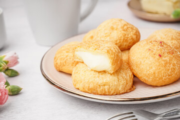 Plate with tasty choux dessert on light background, closeup