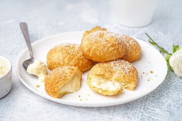Plate with tasty choux dessert on light background