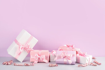 Gift boxes with bows and serpentine on pink background
