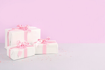Gift boxes with beautiful bows and confetti on pink background