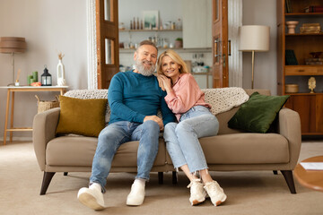 Loving Senior Couple Embracing Posing In Living Room At Home