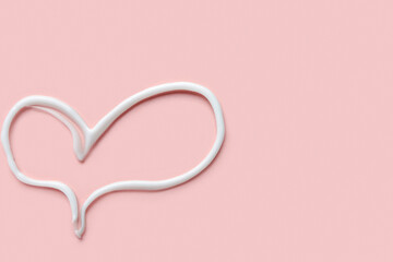 Heart made of sunscreen cream on pink background