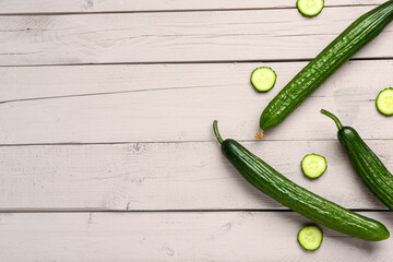 Fresh cucumbers on light wooden background