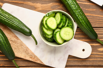 Bowl with fresh cut cucumber on wooden background