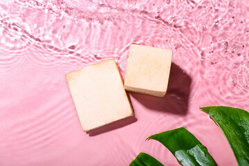 Plaster podiums and monstera leaf in water on pink background