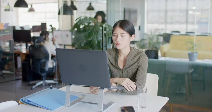 Busy asian casual businesswoman having laptop video call in office in slow motion