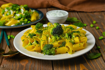 Plate with tasty pasta and broccoli on wooden background