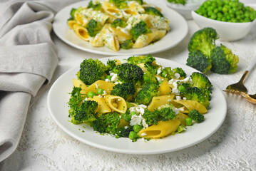 Plate with tasty pasta and broccoli on light grunge background