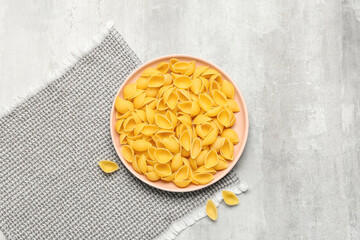 Plate with raw conchiglie pasta on grunge background