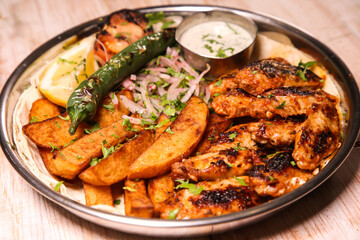 Chicken wings platter with wedges, dip, chilli, onion and lemon served in dish isolated on background top view of arabic food