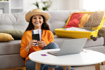 Excited young lady planning vacation, sitting in front of laptop