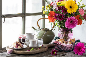 Tea and scones on a rustic wooden table with a bouquet of beautiful flowers. - obrazy, fototapety, plakaty