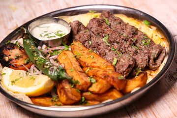 Kebab Laham or lamb kabab with salad, wedges, lemon and dip served in dish isolated on background top view of arabic food
