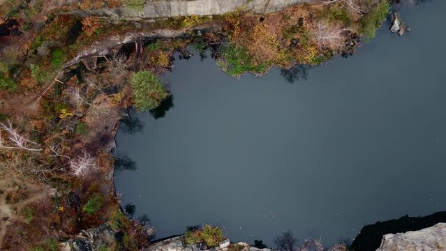 Picturesque aerial view of landscape with emerald lake and rocks in the middle of a coniferous autumn forest in Korostyshiv granite quarry, Zhytomyr district, northern Ukraine. Zhytomyr canyon.