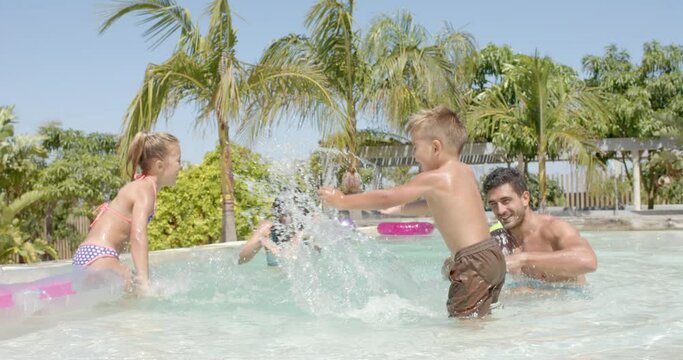 Happy caucasian family playing with inflatables in swimming pool
