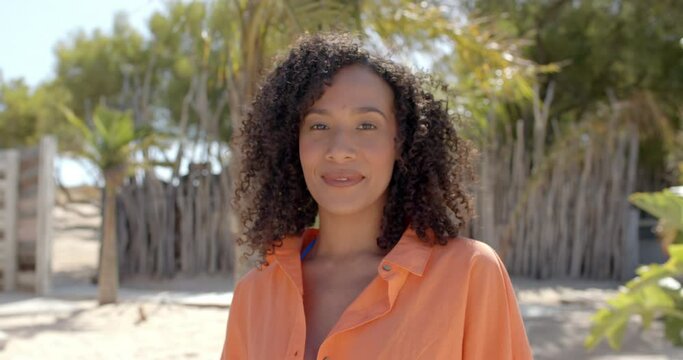 Portrait of happy biracial woman looking at camera at beach house