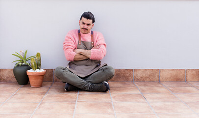 young handsome man gardering and sitting on the floor outdoors