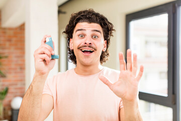 young handsome man with an asthma inhaler at home interior