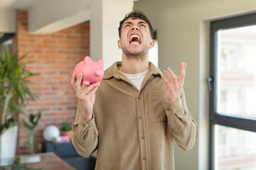 young handsome man screaming with hands up in the air. piggy bank concept