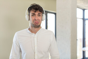 Obraz premium young handsome man feeling sad and whiney with an unhappy look and crying. listening music with headphones