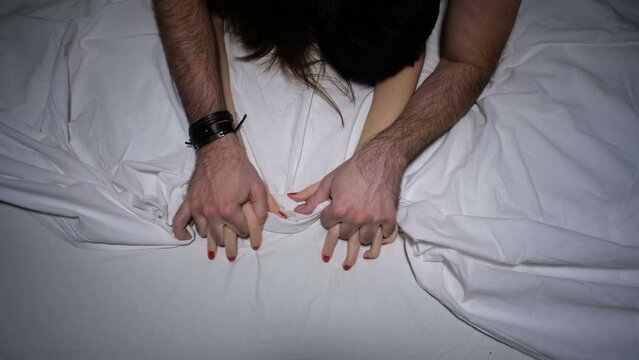 Couple holding hands having sex in bedroom