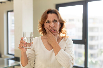 middle age pretty woman with mouth and eyes wide open and hand on chin. water glass