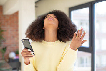 pretty afro black woman screaming with hands up in the air. smartphone concept