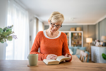 Senior woman mature caucasian female read book at home wear eyeglasses