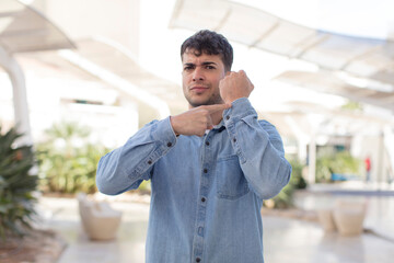 young handsome man looking impatient and angry, pointing at watch, asking for punctuality, wants to be on time