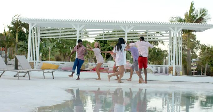 Happy diverse group of friends dancing and playing at swimming pool