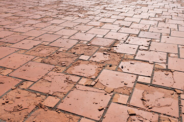Rote quadratische Bodenplatten, die durch Witterungseinflüsse oder Materialfehler beschädigt...