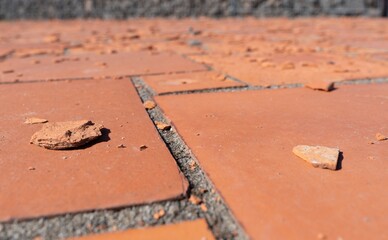 Rote quadratische Bodenplatten, die durch Witterungseinflüsse oder Materialfehler beschädigt...